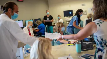 Doctors, nurses, and other caregivers work in a busy nurses station setting at South Shore Hospital.
