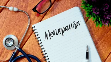 The word menopause on a notebook with a stethoscope and glasses