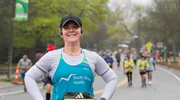A runner from Team South Shore Health smiles as she poses for a photo on the course during the 2022 race.
